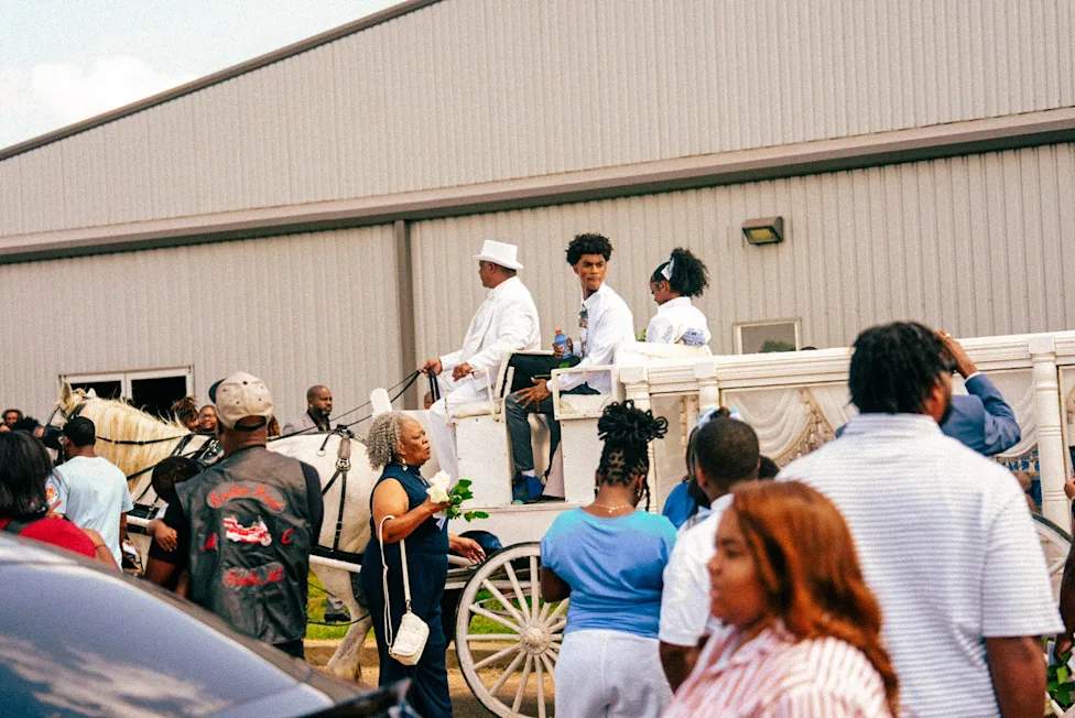 A crowd of mourners dressed in teal and blue gather outside the Hosanna Family Worship Center in Pope, Mississippi for the funeral of one-year-old Kohen Wiley on June 27, 2026