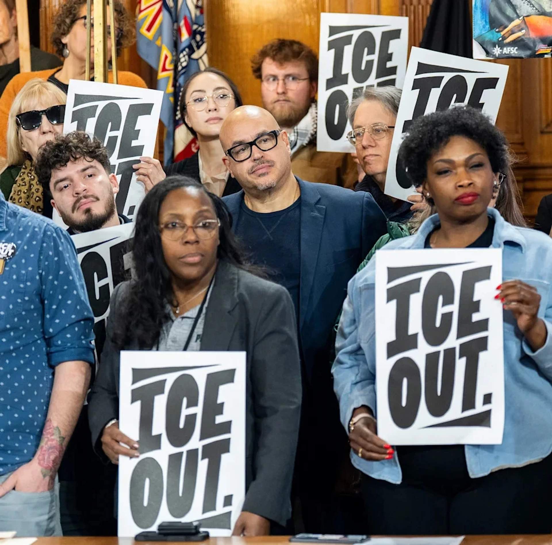 Crowd of protesters at a community rally holding signs against ICE operations
