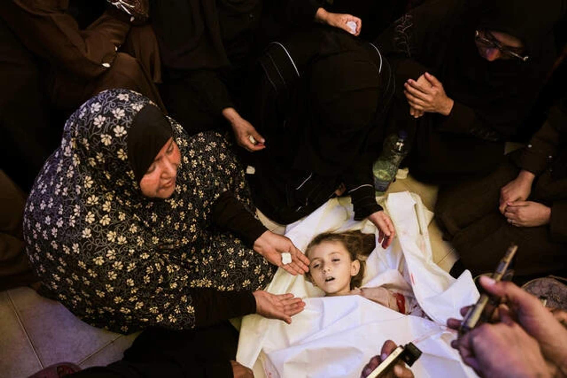 Palestinian relatives mourning around the shrouded body of a six-year-old girl in a hospital in Khan Younis