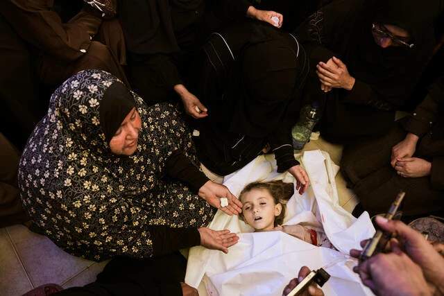 Palestinian relatives mourning around the shrouded body of a six-year-old girl in a hospital in Khan Younis