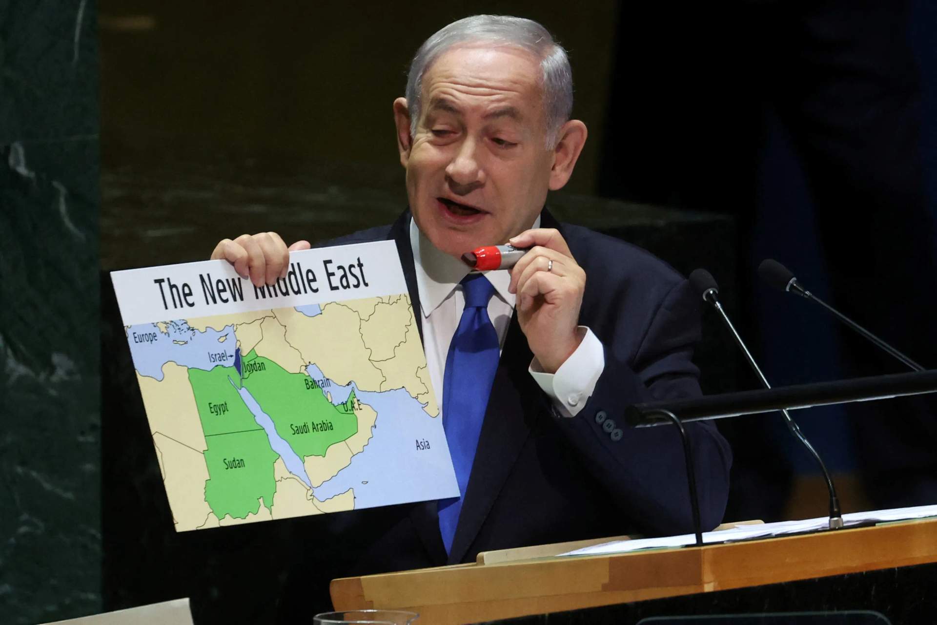 Benjamin Netanyahu stands at a podium holding up a map that shows Israel extending across the entire territory, with no indication of Palestinian territories. He points to the map with his right hand while addressing the UN General Assembly.