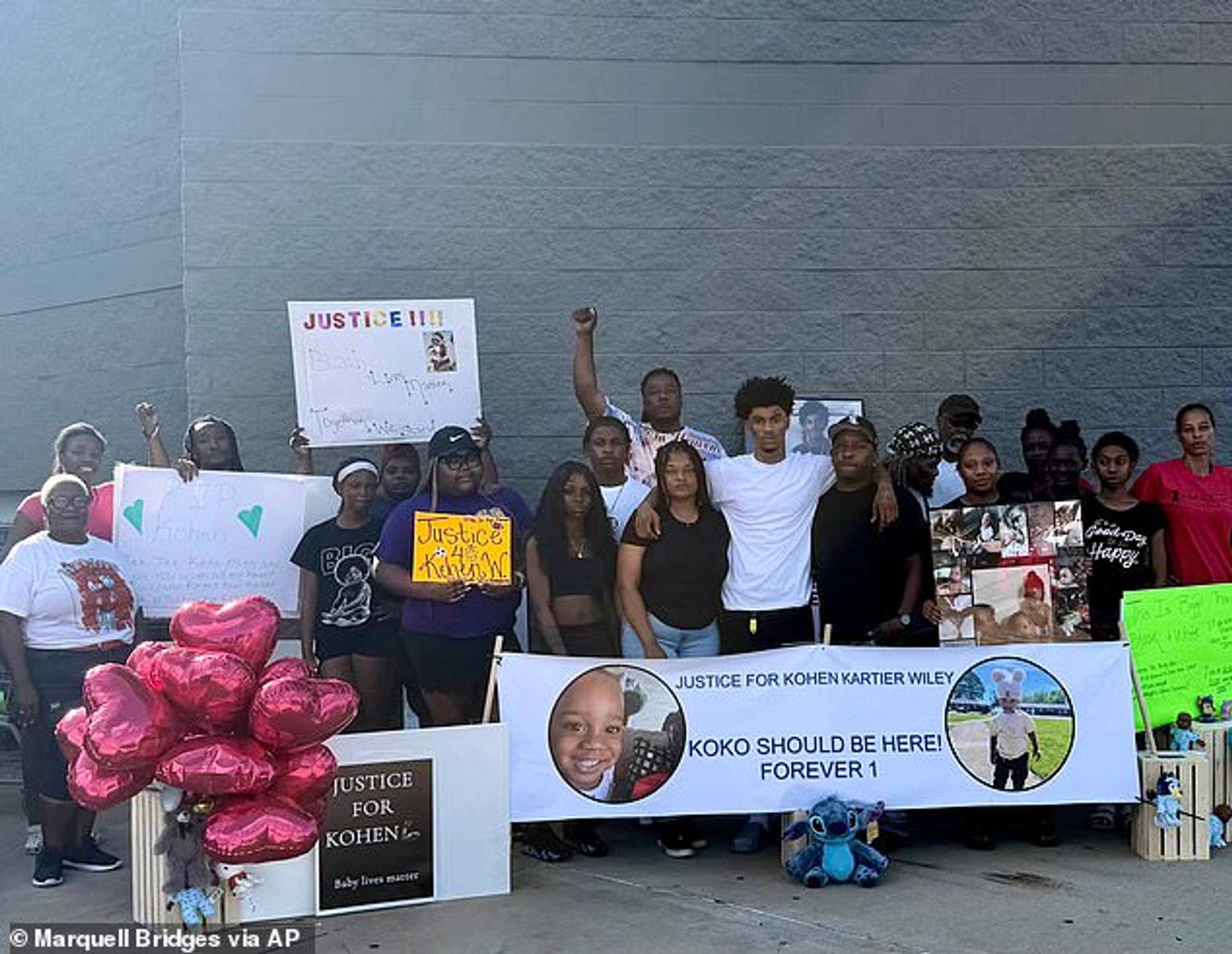 Flowers, balloons, and handwritten signs arranged on the pavement outside a Walmart store entrance as a memorial for one-year-old Kohen Wiley in Senatobia, Mississippi