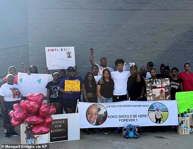 Flowers, balloons, and handwritten signs arranged on the pavement outside a Walmart store entrance as a memorial for one-year-old Kohen Wiley in Senatobia, Mississippi