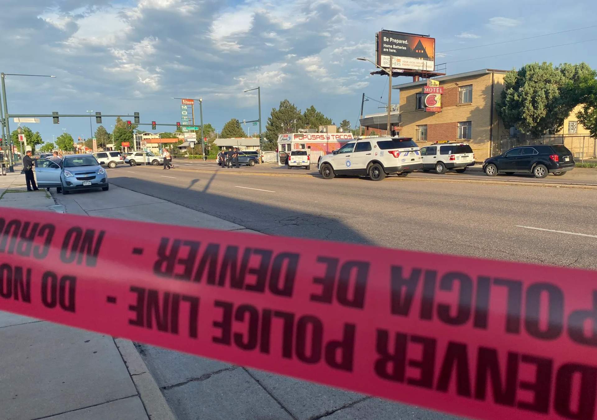 Police investigation at a shooting scene on a Denver street with evidence markers and emergency vehicles