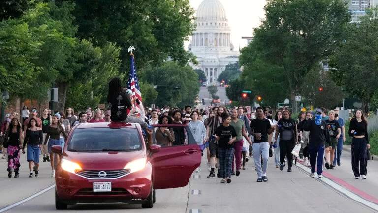 A protester raises a clenched fist from a car window on a Madison street