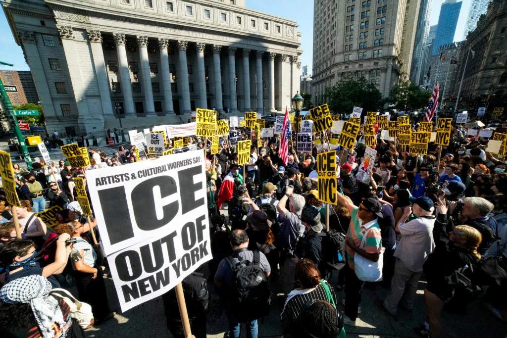 Crowd of protesters with signs and banners demonstrating against ICE in New York City
