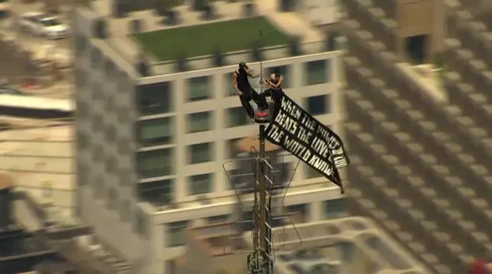 Angela & Ivan atop the spire of the Empire State building with banner reading "When the power love beats the love of power the will know peace"