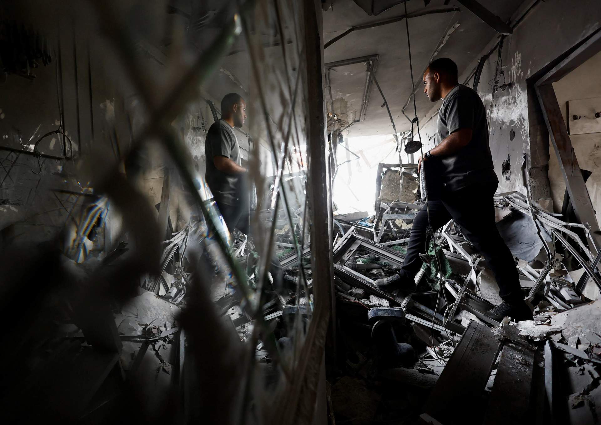 A man standing amid concrete rubble and twisted metal from a destroyed residential building in Gaza after an Israeli airstrike