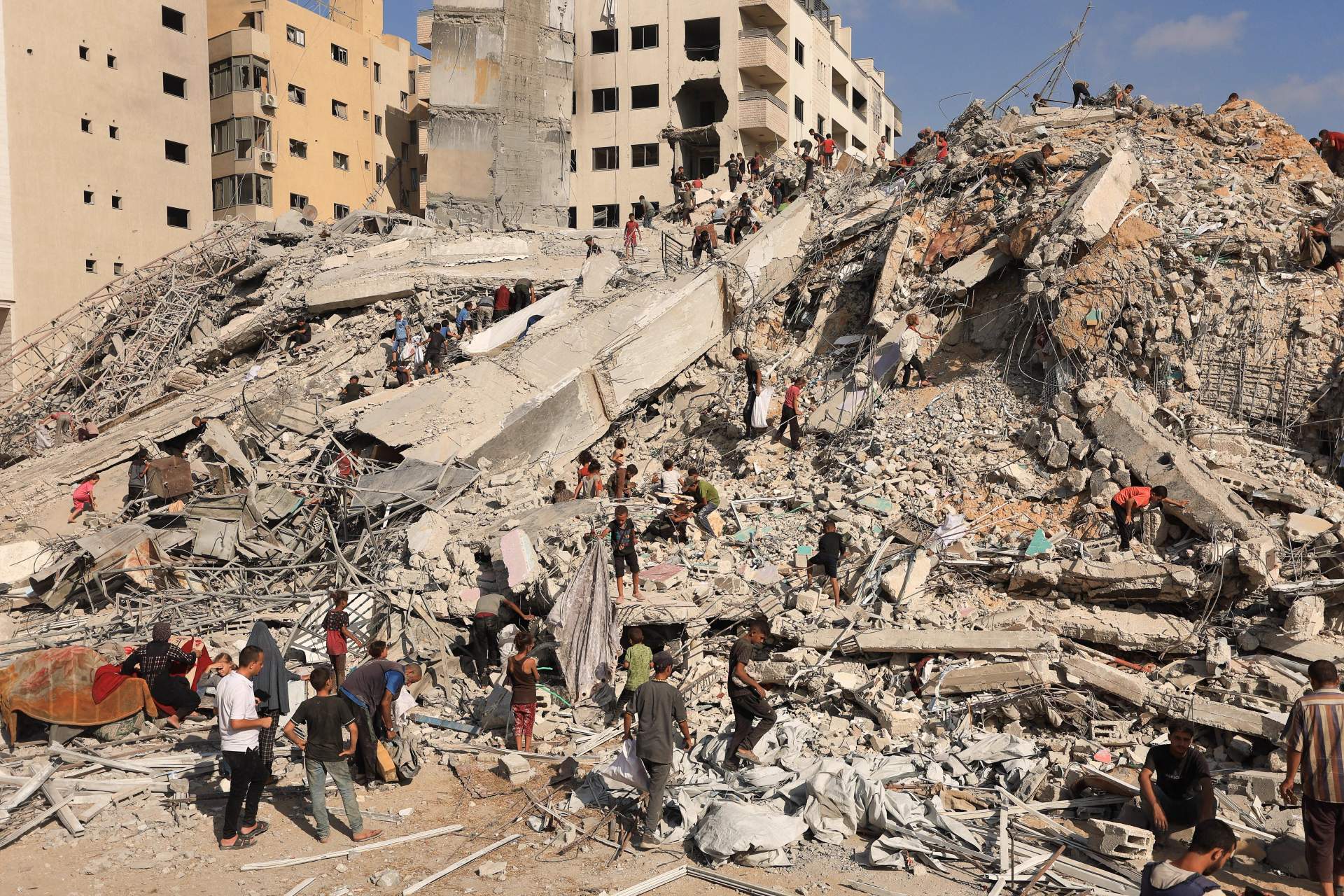 Palestinian rescue workers and civilians inspect the rubble of a destroyed residential high-rise building in Gaza City after an Israeli air strike in September 2025