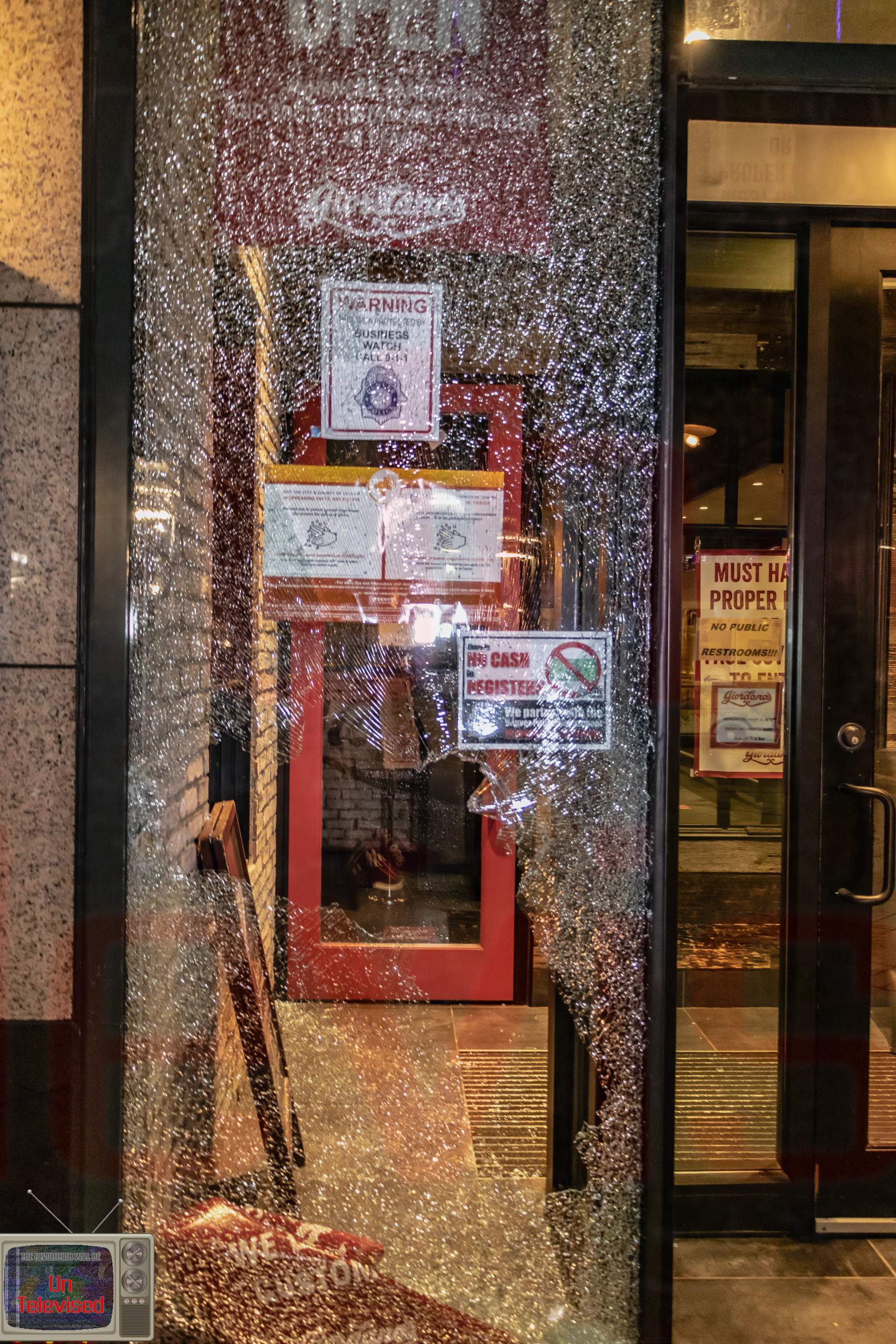 The entrance of Giordano's restaurant with its glass door/window shattered, COVID signage about no cash and proper attire posted. [Radical Edward - Untelevised Media]