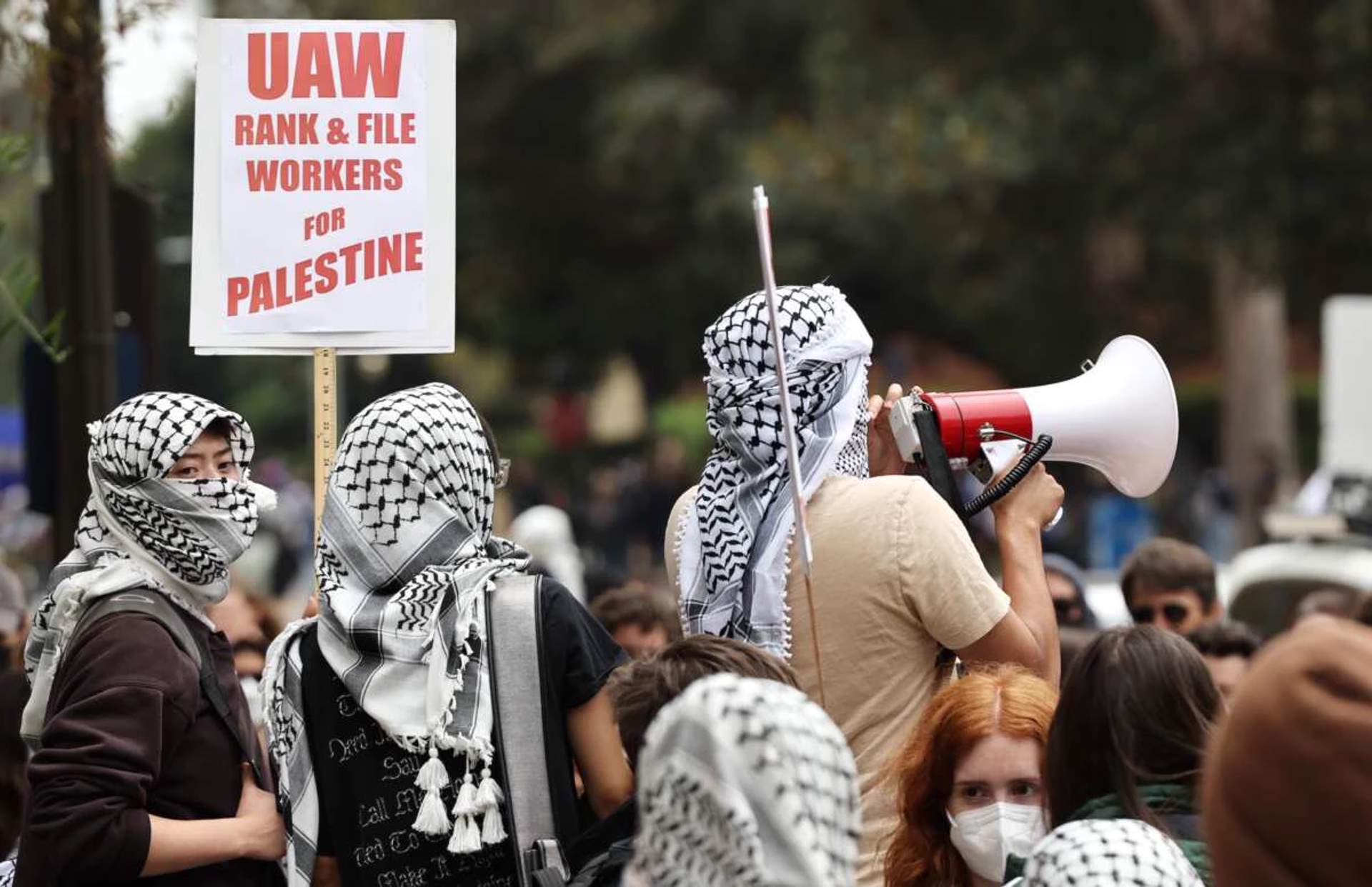 Pro-Palestinian protesters carrying signs reading UAW Rank-and-File for Palestine and Free Palestine marching outside a UAW building