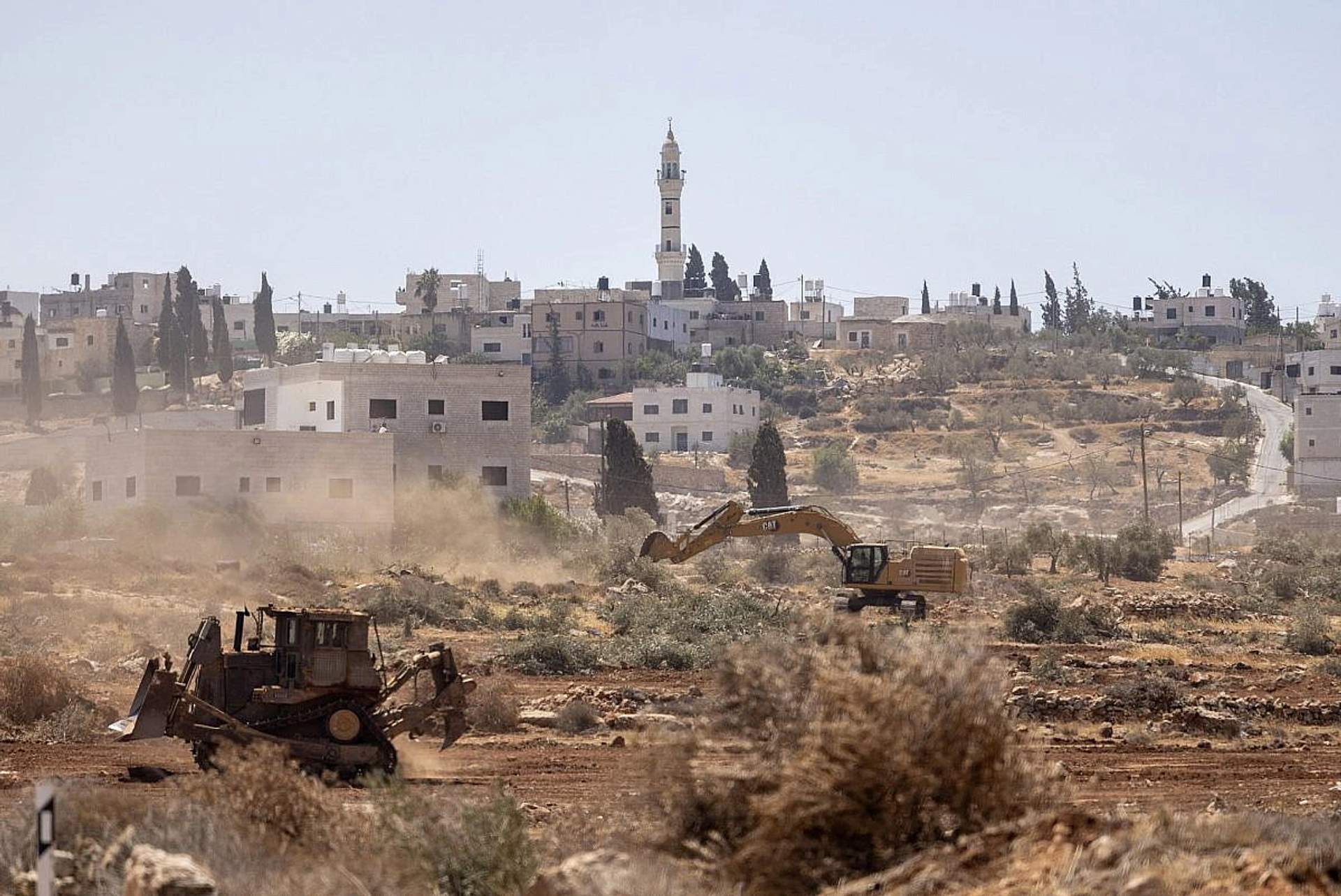 Bulldozers operated by Israeli settlers and soldiers uproot olive trees near the village of Al-Mughayyir, in the occupied West Bank, August 23, 2025. (Avishay Mohar/Activestills)