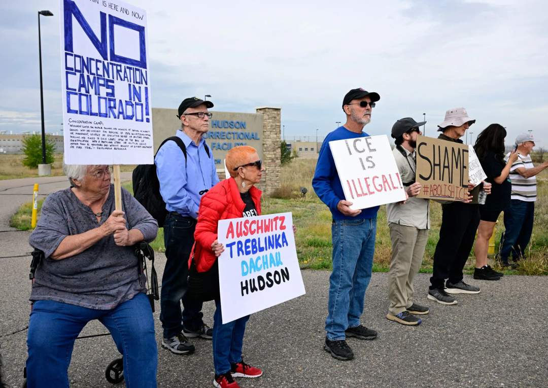 Protesters holding signs outside the fenced gates of the Hudson Correctional Facility