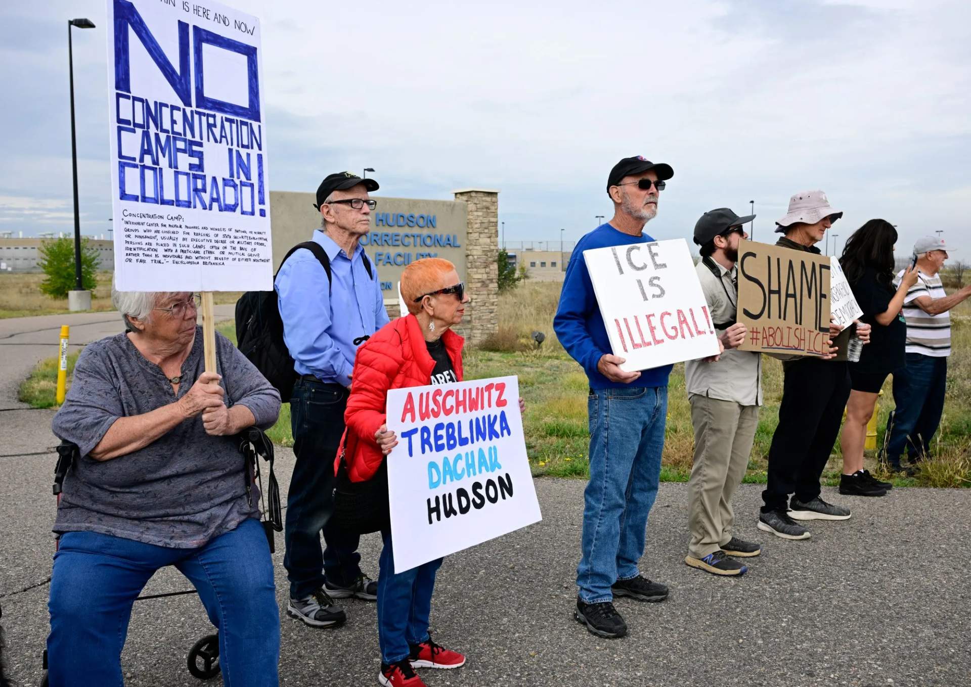 Protesters holding signs outside the fenced gates of the Hudson Correctional Facility