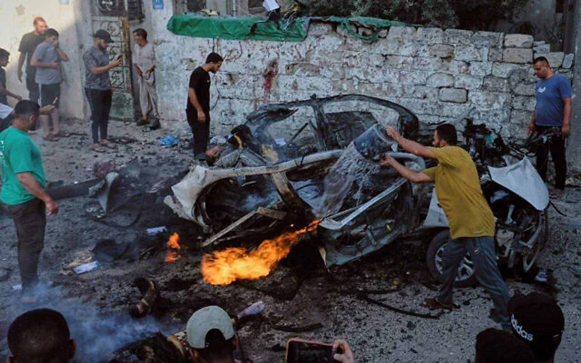 Palestinians try to extinguish a burning car after an Israeli military strike in Gaza City on August 2, 2026, as 18 Palestinians were killed across the strip.