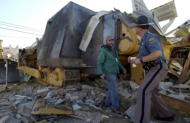 Colorado State Patrol Captain Gary Torgerson and Grand County Emergency Manager James Holahan examine the armored bulldozer in Granby Colorado June 5 2004