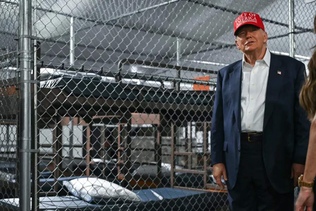 Donald Trump smirks as he poses in front of caged beds while touring a deportation detention facility.