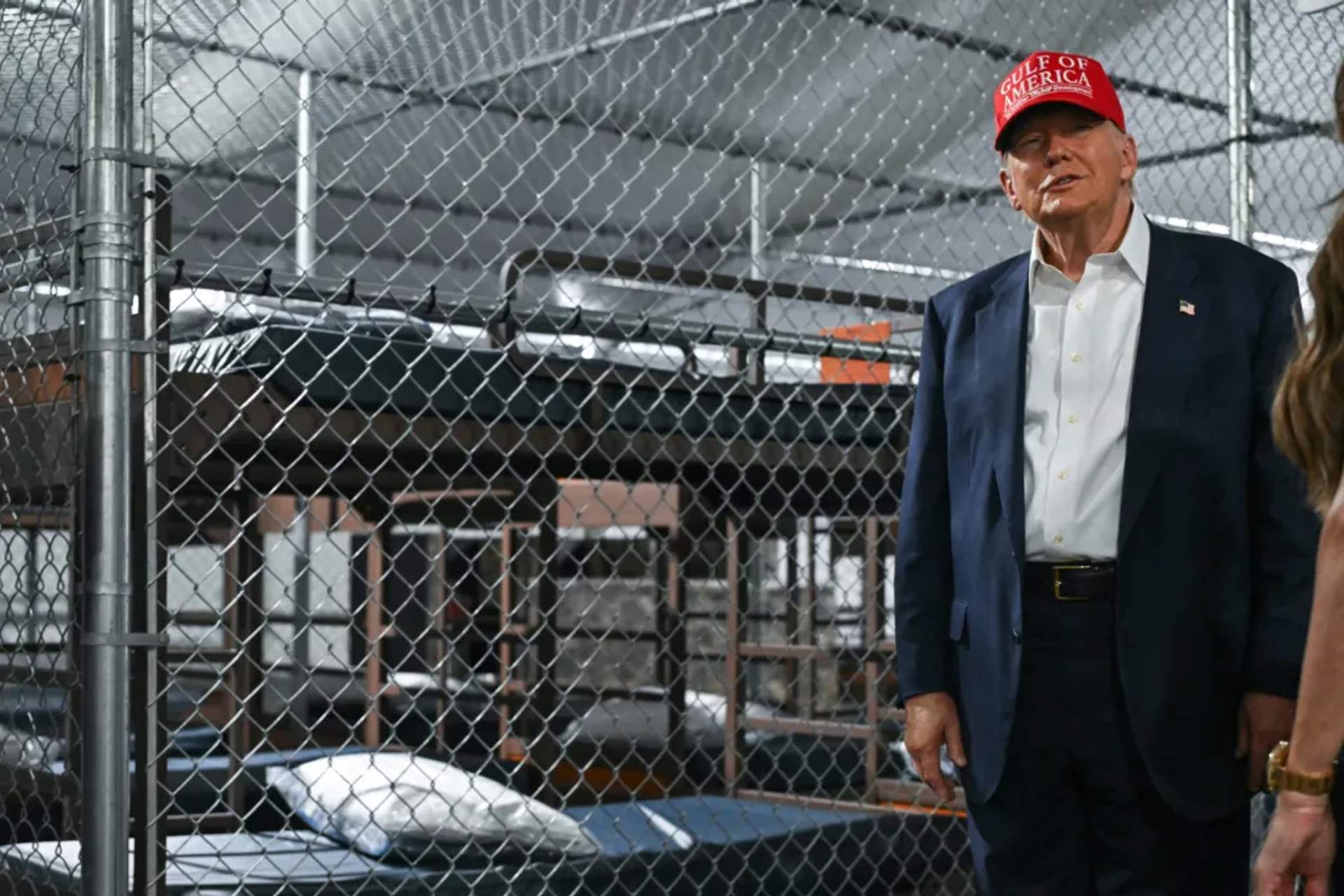 Donald Trump smirks as he poses in front of caged beds while touring a deportation detention facility.