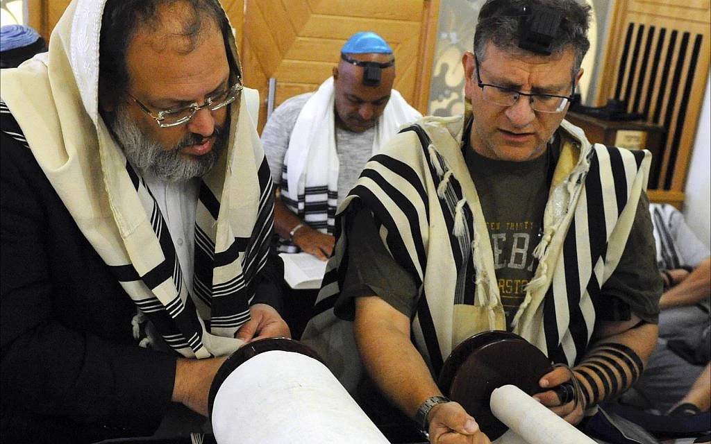 Orthodox Jewish men reading Torah scrolls inside the Larnaca synagogue in Cyprus