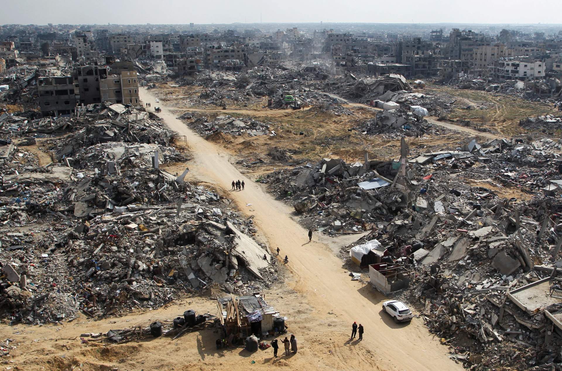 Wide aerial view of total destruction across a neighborhood in northern Gaza, nothing standing but rubble and broken concrete