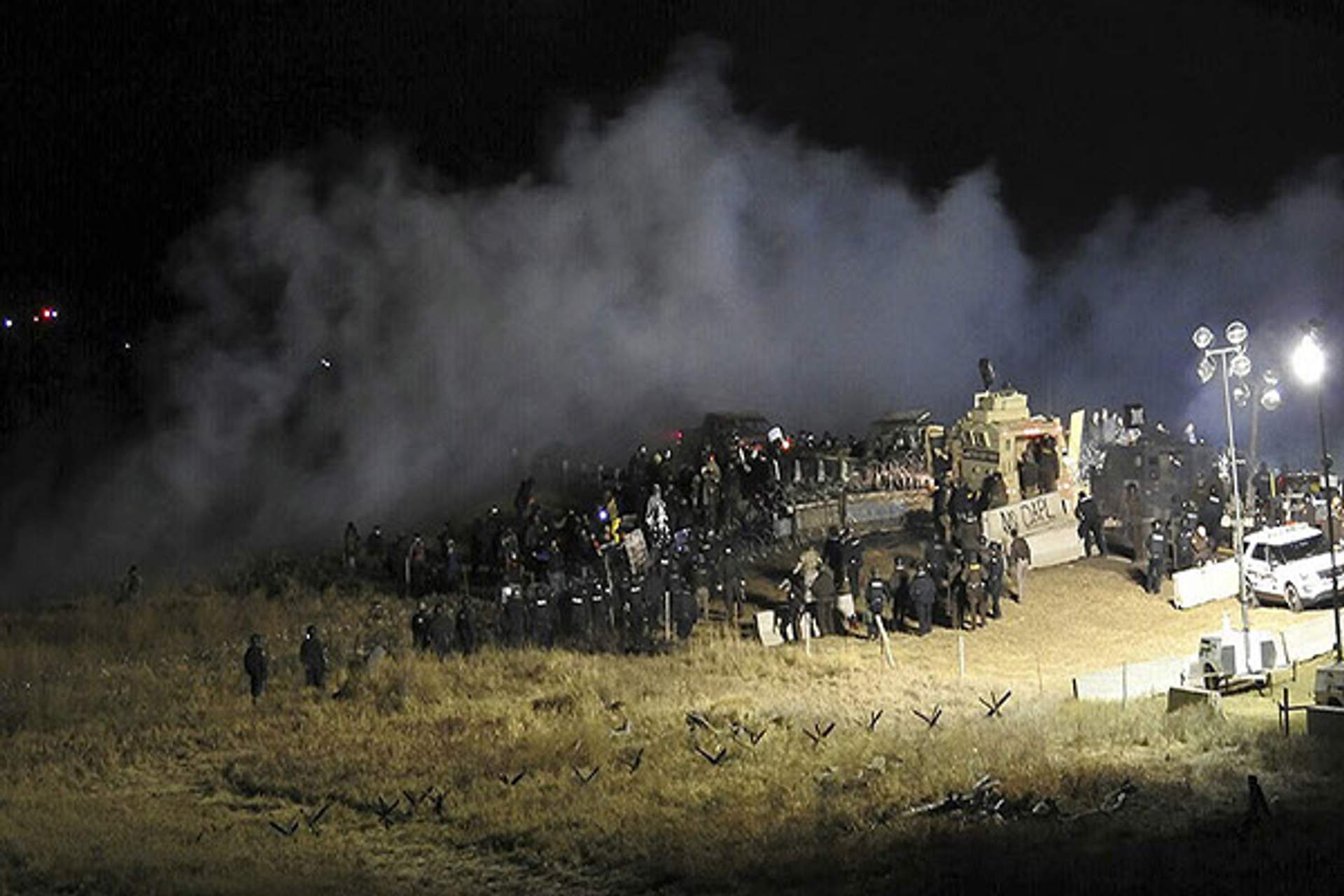 Massive cloud of tear gas behind large amount of law enforcement. 