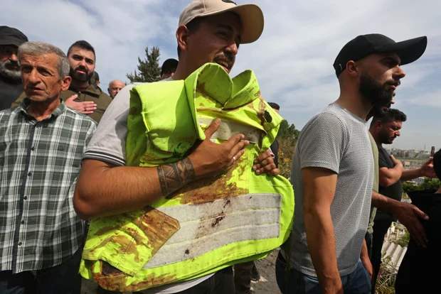 A man carries the blood-stained jacket of a paramedic killed in Mayfadoun, during his funeral procession.