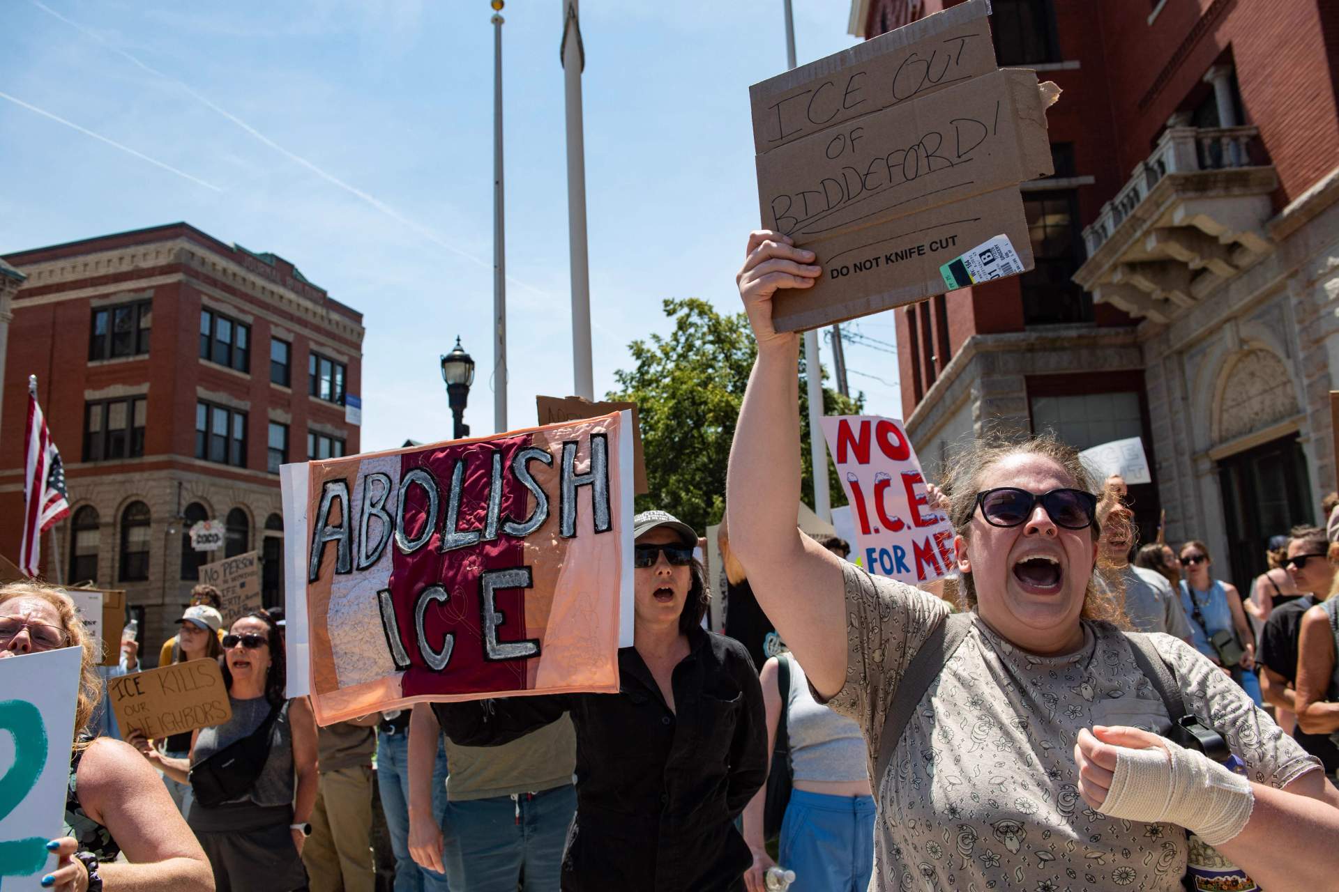 Crowd of protesters holding signs against ICE in Biddeford, Maine after a fatal shooting by immigration agents