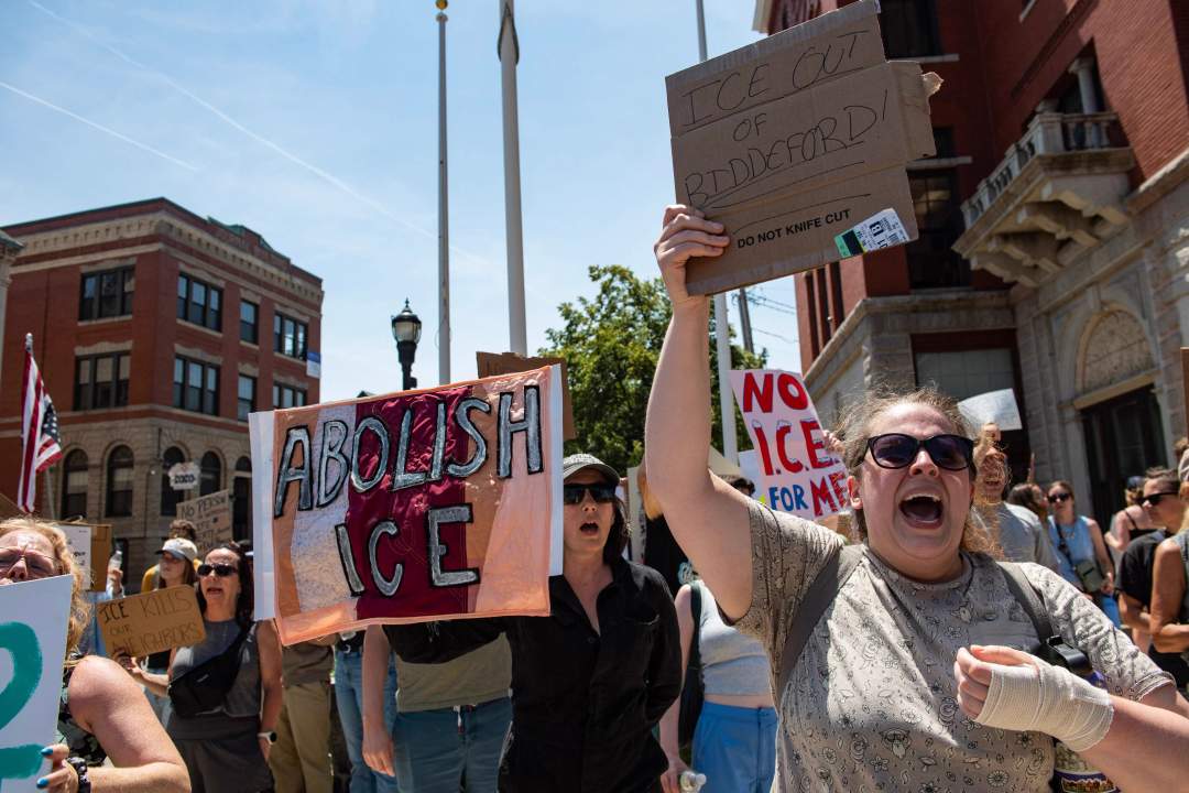 Crowd of protesters holding signs against ICE in Biddeford, Maine after a fatal shooting by immigration agents