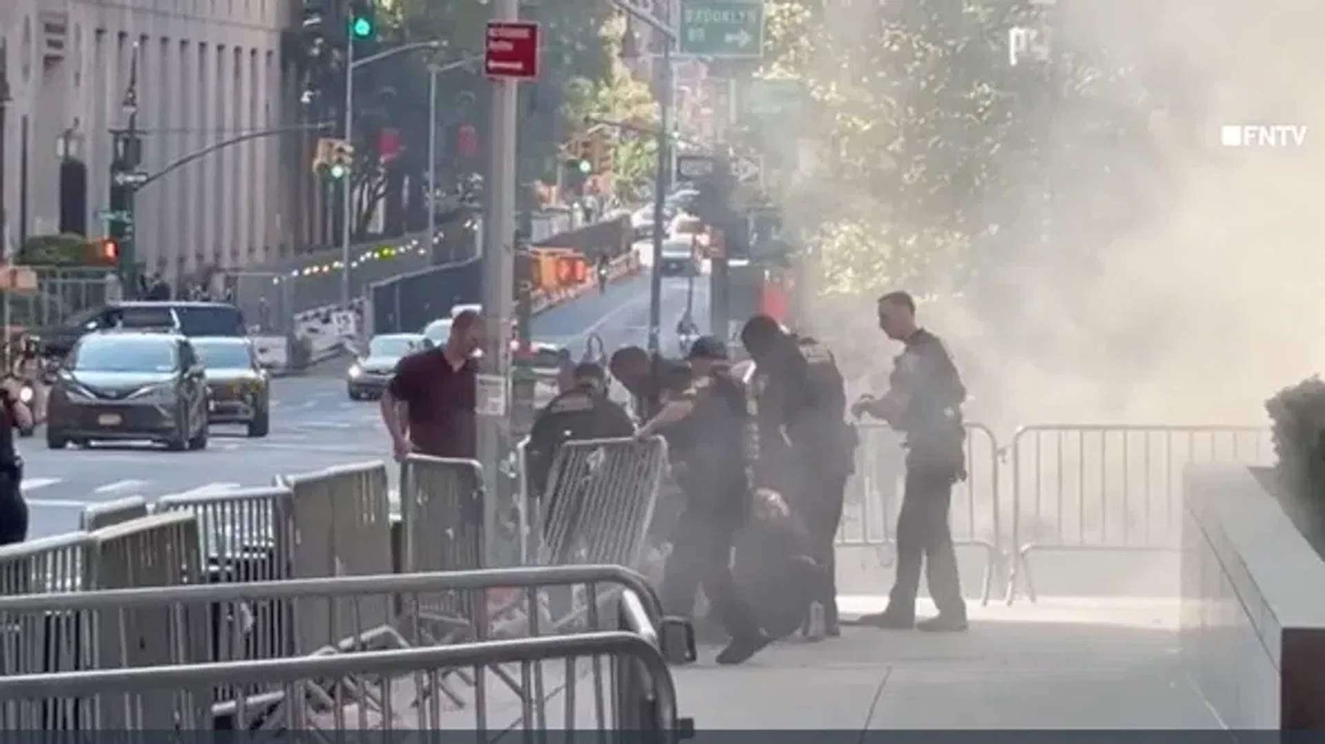 Officers tackle suspect of the shopping cart fire as smoke fills the sidewalk.