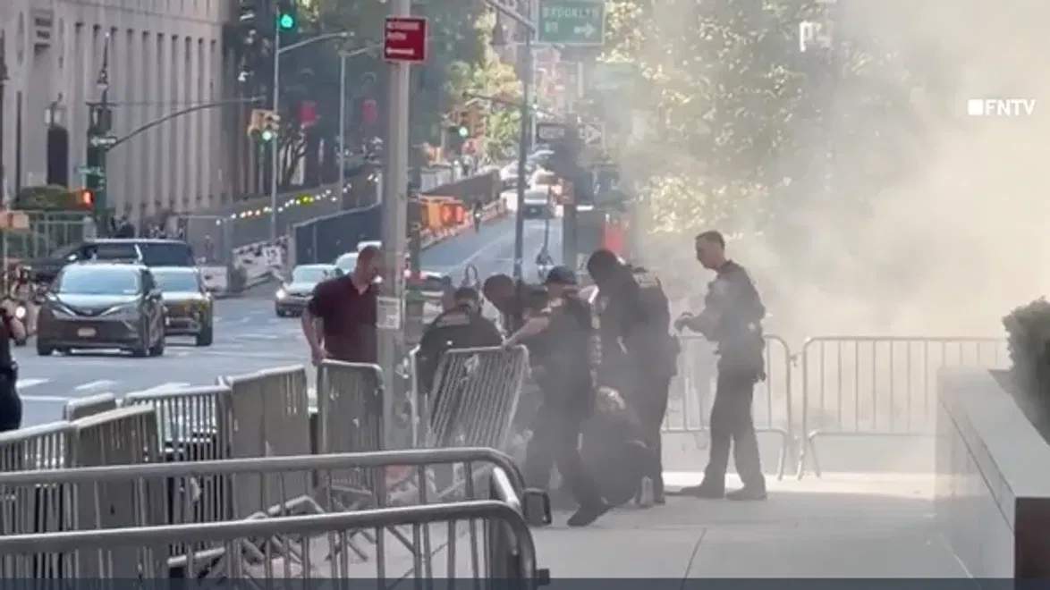 Officers tackle suspect of the shopping cart fire as smoke fills the sidewalk.