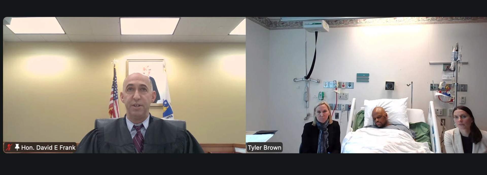 Tyler E. Brown lying in a hospital bed during his virtual arraignment in Cambridge District Court on May 14, 2026