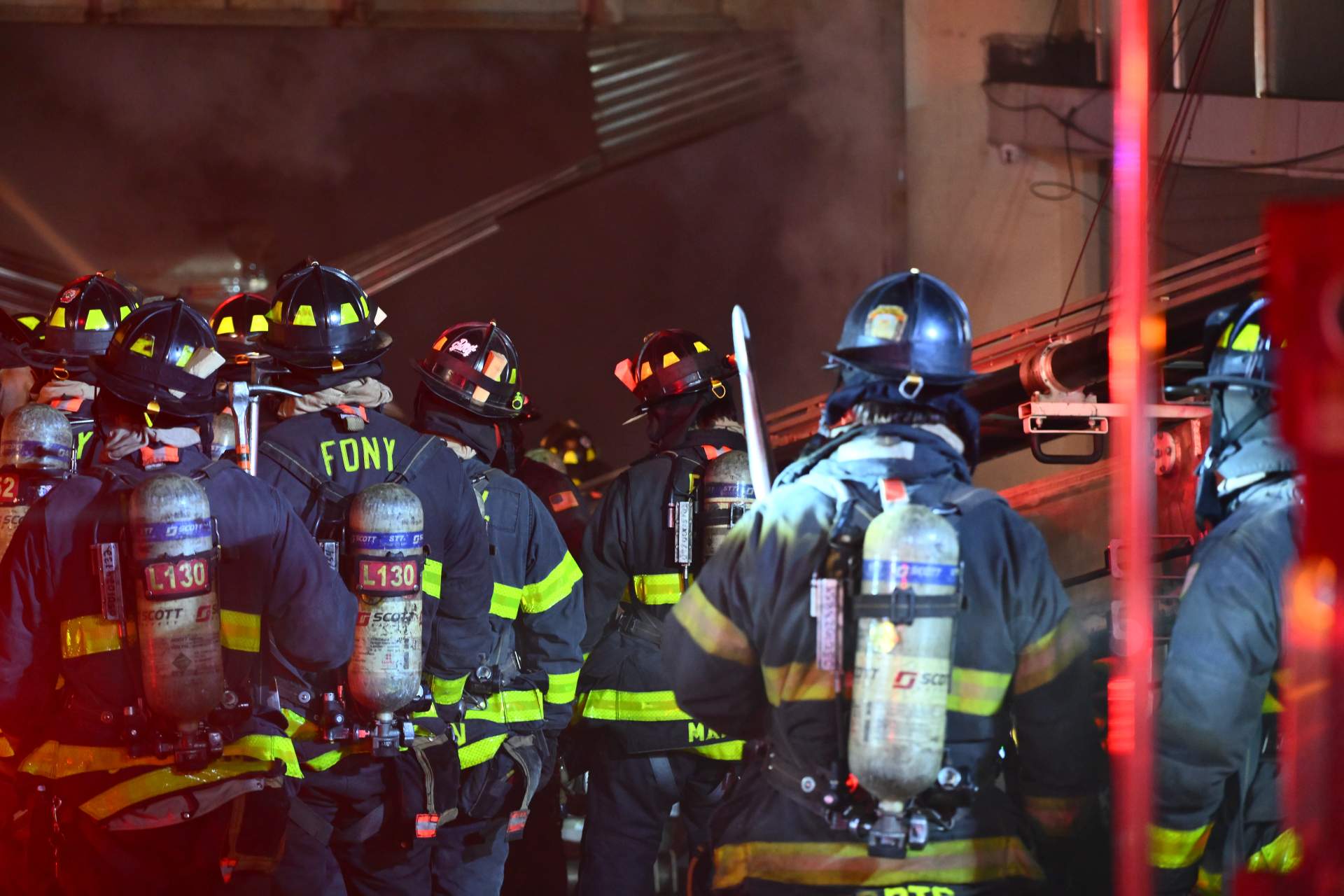 FDNY firefighters work through the night to contain the massive blaze at the College Point lumberyard, with smoke billowing across the Queens skyline.