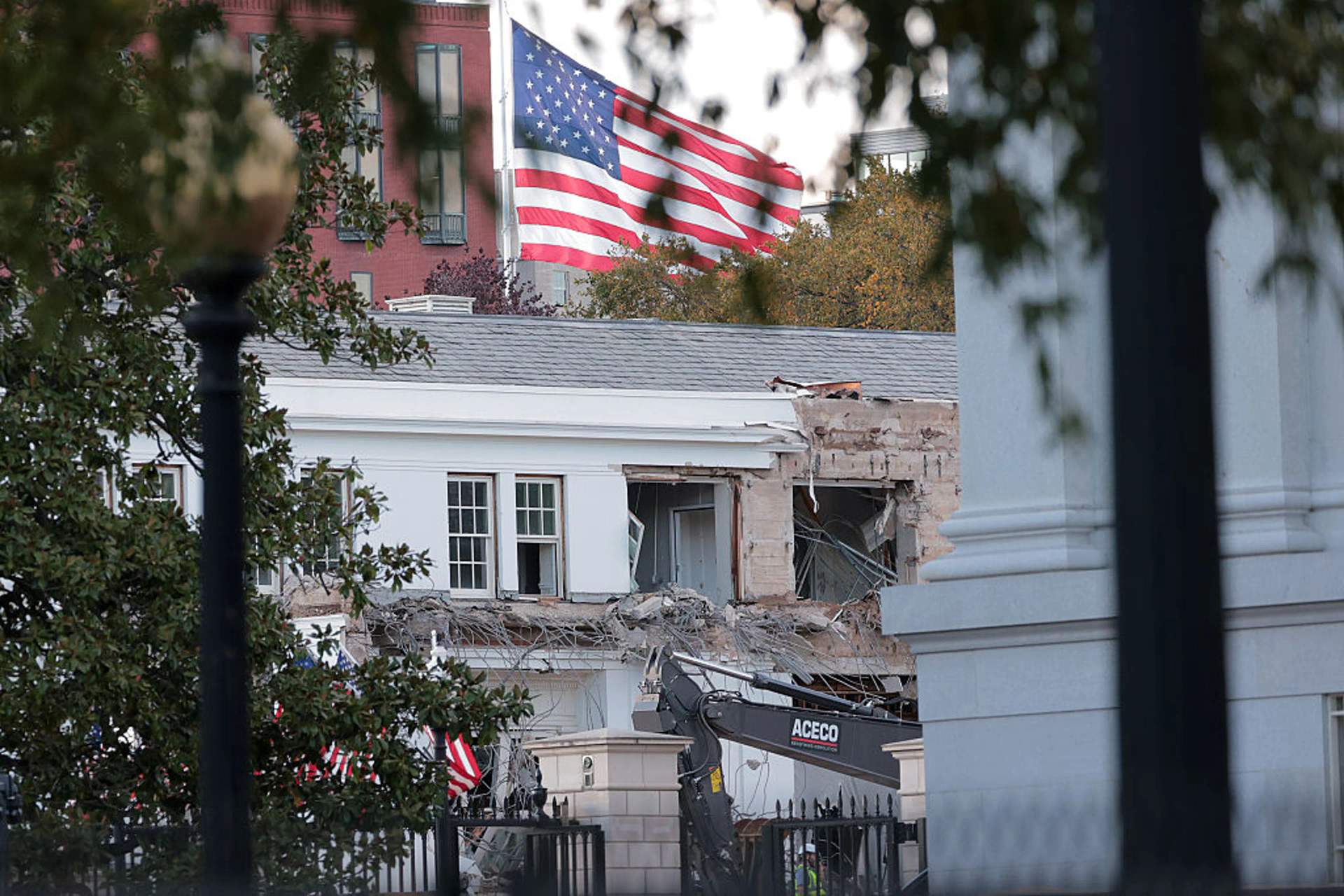 Aerial view showing multiple construction cranes and exposed structural framework at the site where the White House East Wing once stood, with the rest of the White House complex visible nearby