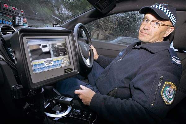 Wollongong highway patrolβs Senior Constable Phil Roddy demonstrates the automatic number plate recognition technology.
