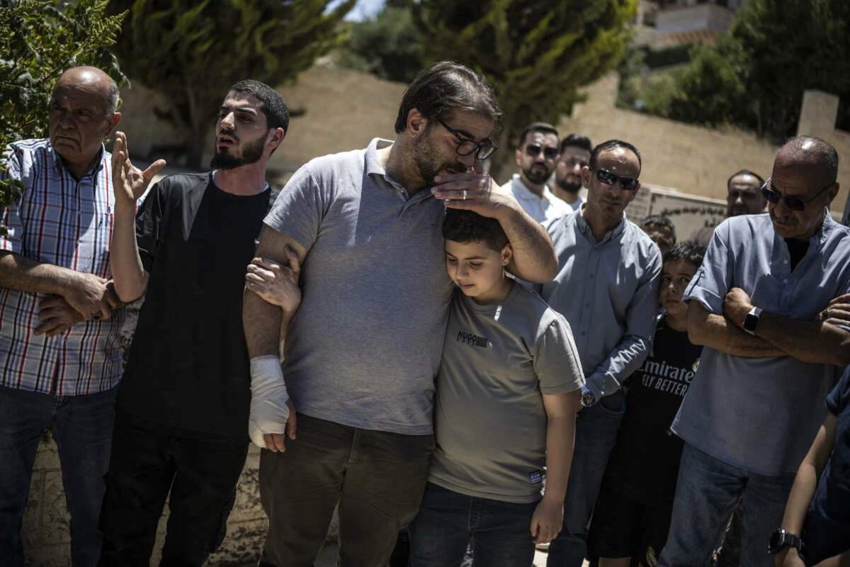 Fahd Abu Haikal comforts his elder son Kinan after burying seven-month-old Sam in Hebron, June 6, 2026.