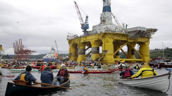 Kayaktivists in small boats surround the Polar Pioneer drilling rig in Seattle's harbor.