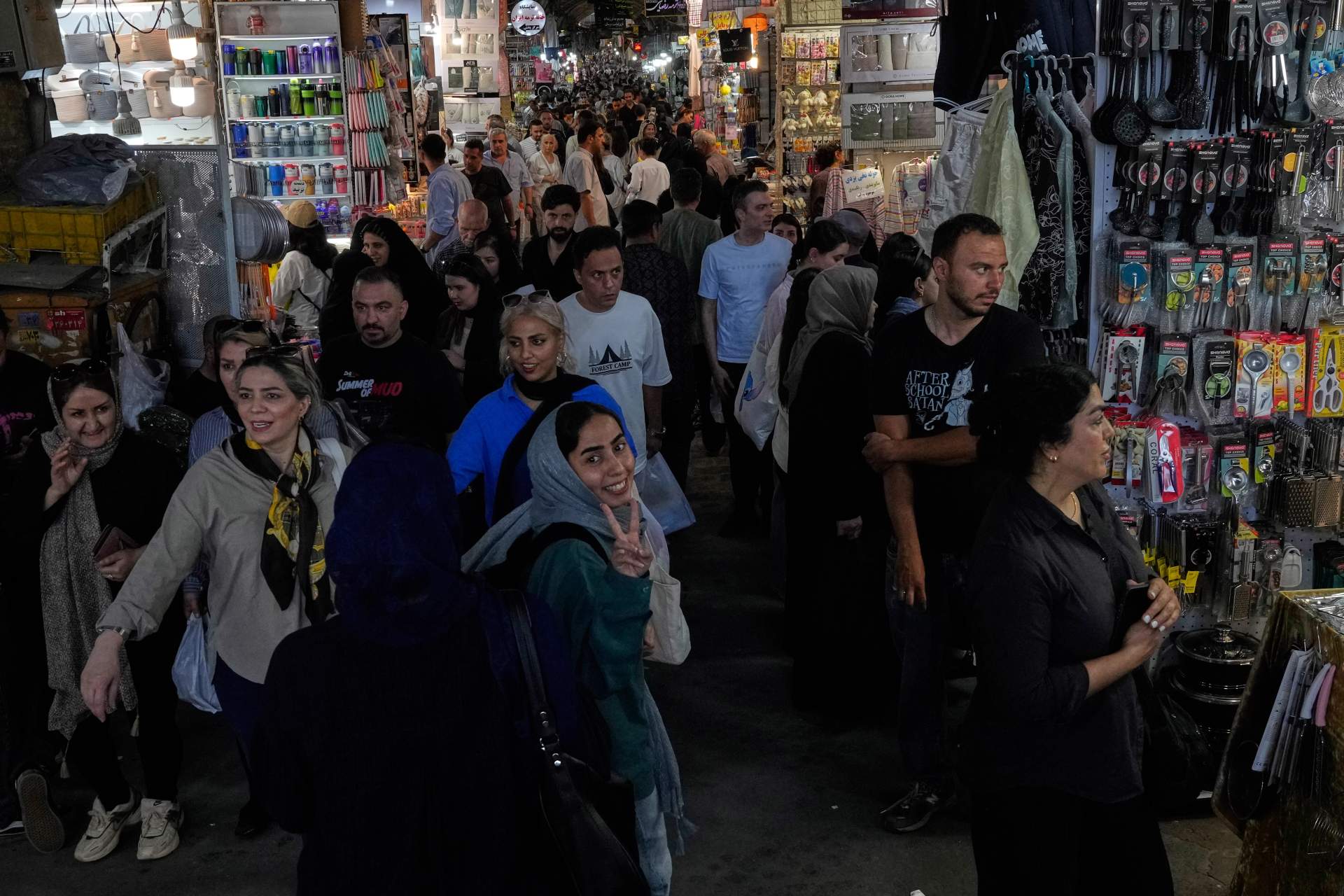 An Iranian woman walking through a traditional bazaar in Tehran flashing a victory sign during wartime, July 16, 2026