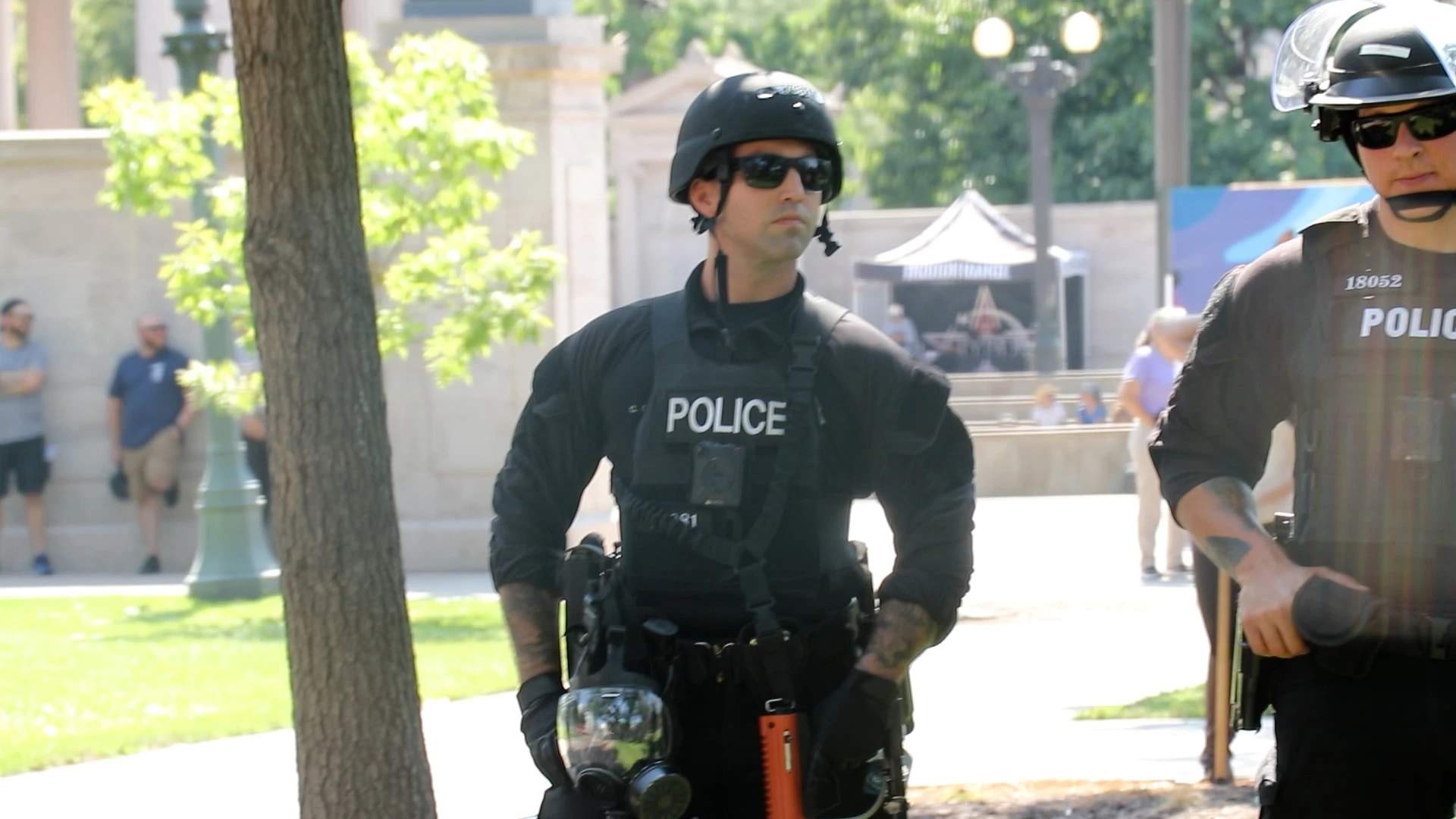 Riot police behind the fence with weapons at the ready.