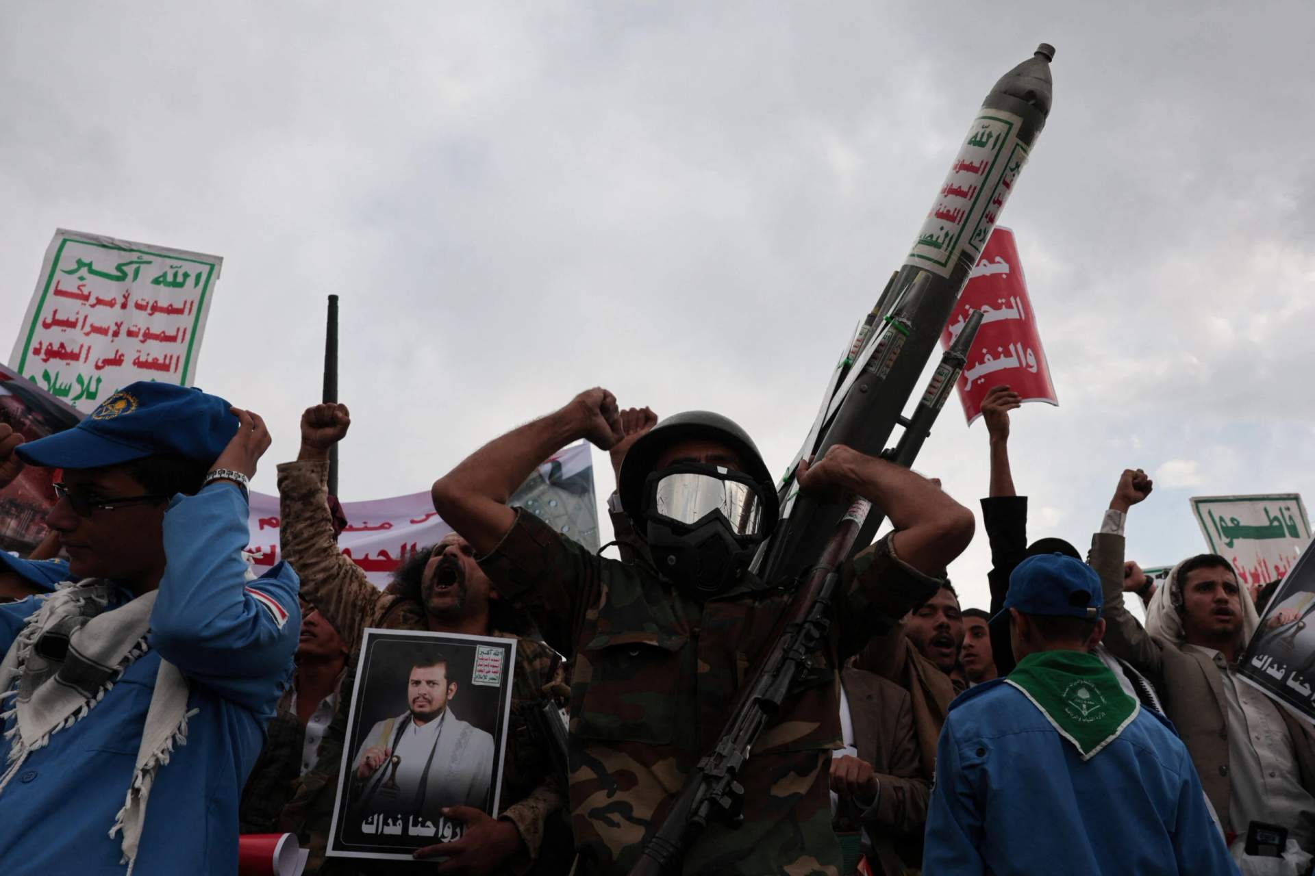Large crowd of Houthi supporters gathered at a nighttime rally in Sanaa, Yemen, many holding flags and placards