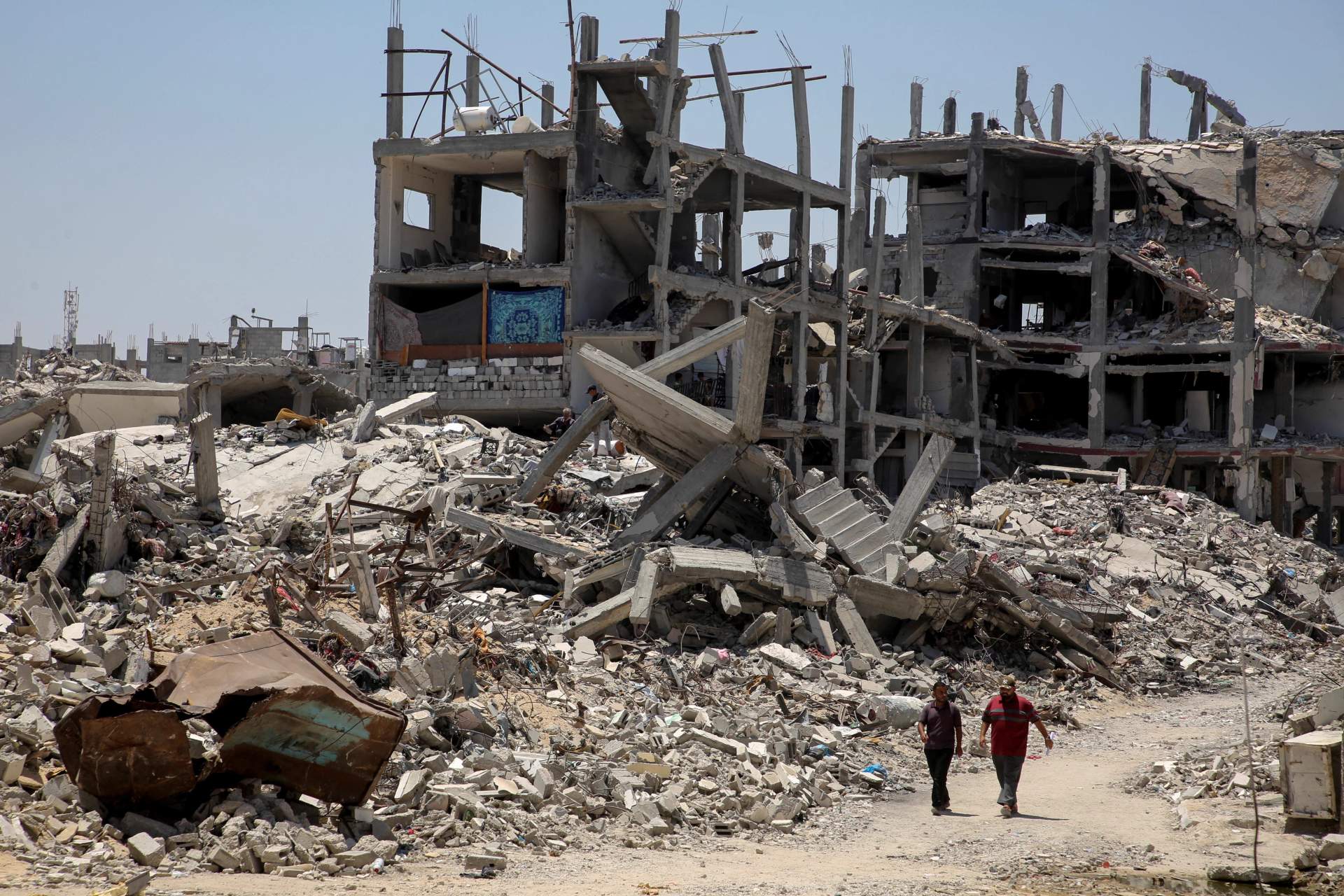 Vast landscape of destroyed multi-story buildings reduced to rubble in Khan Younis, Gaza, under clear sky