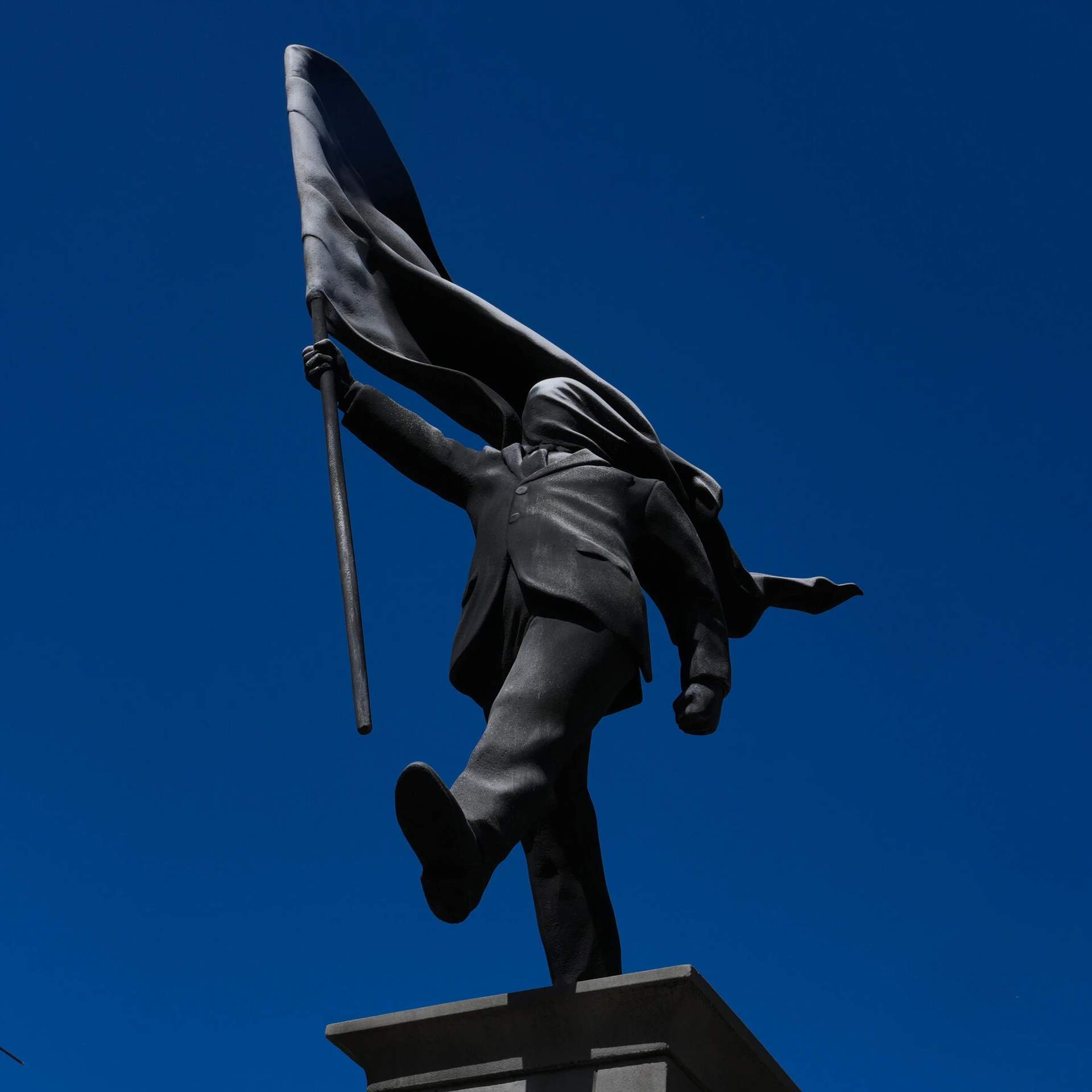 Suited figure blindly marching off his pedestal 