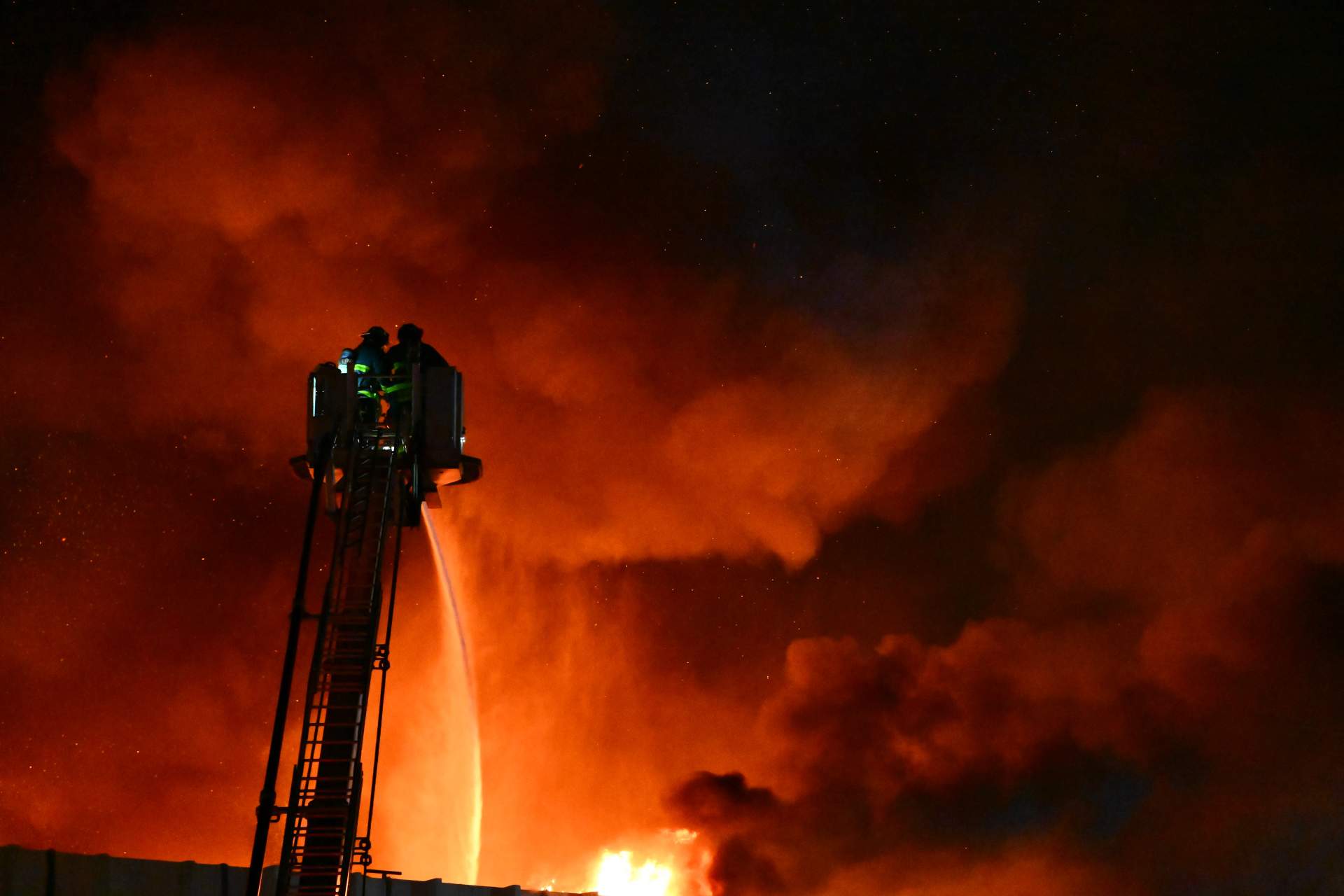 The inferno lights up the night sky over College Point as flames consume the 64,000-square-foot lumberyard and cabinetry business.