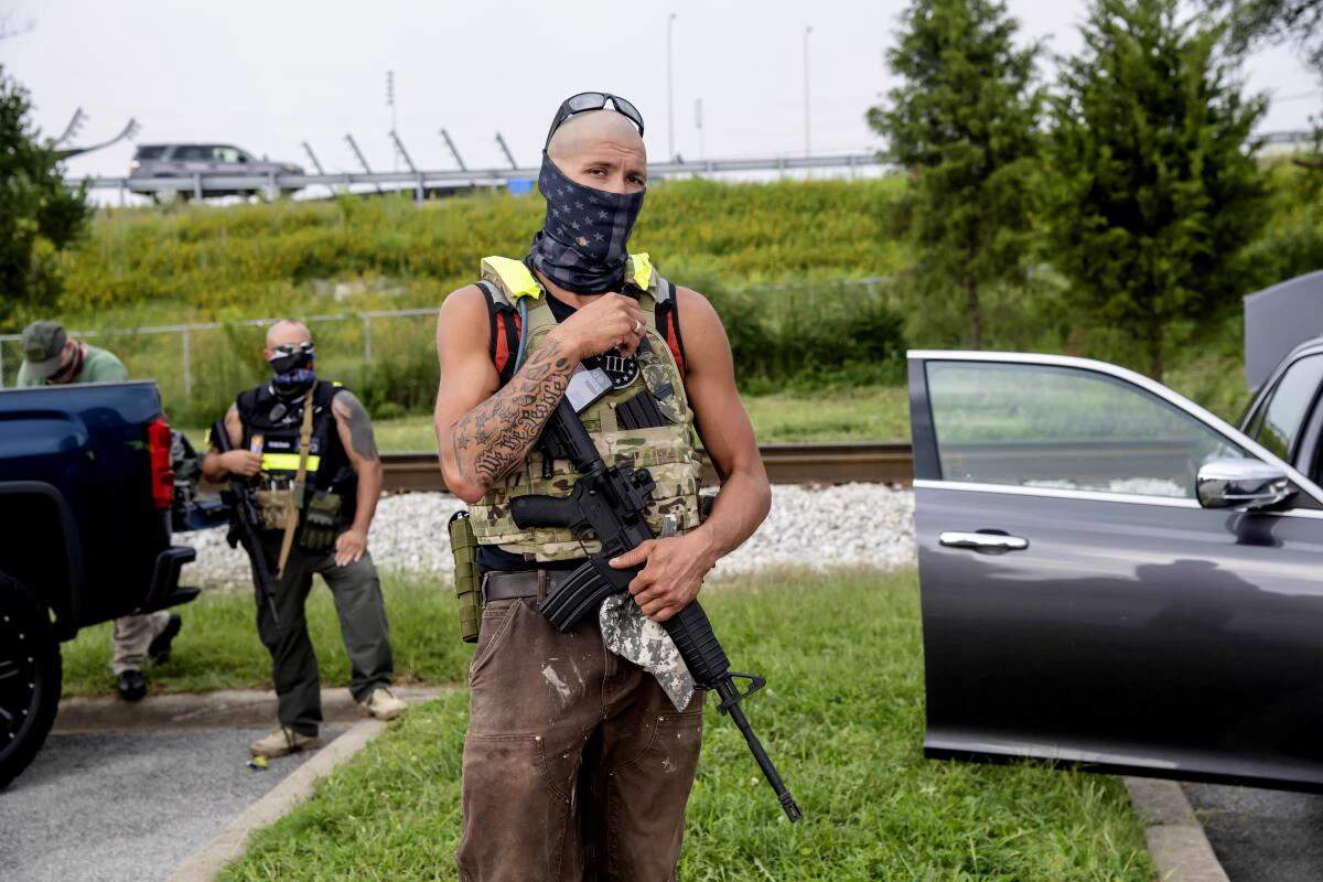 Three Percenters militia members standing in parking lot with rifles