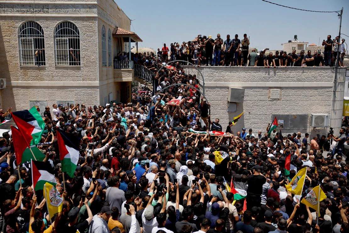 Mourners carrying bodies wrapped in shrouds during funeral procession for Palestinians killed by settlers in the West Bank