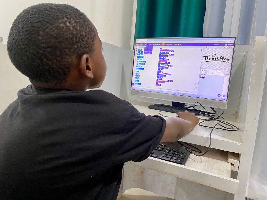 A Junior Explorer building a project in Scratch on a desktop computer