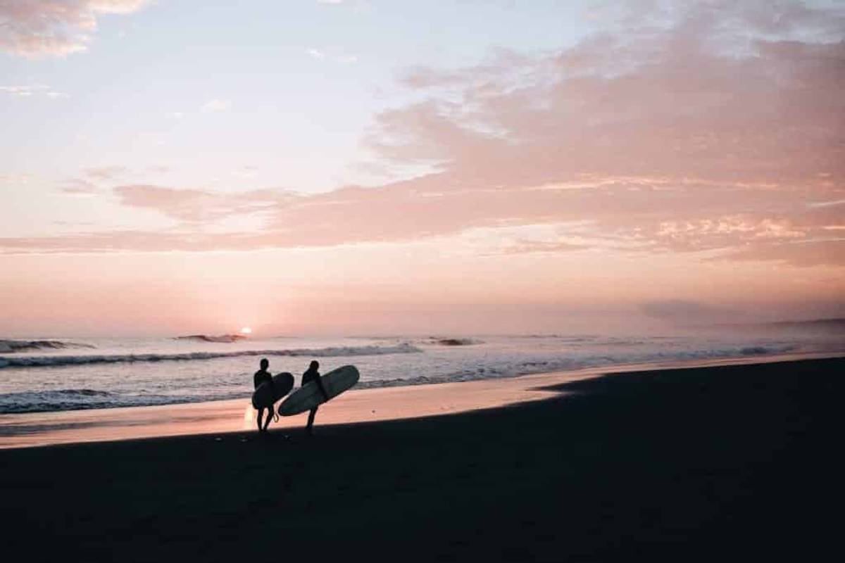 Surf instructor walks with a pupil up the beach