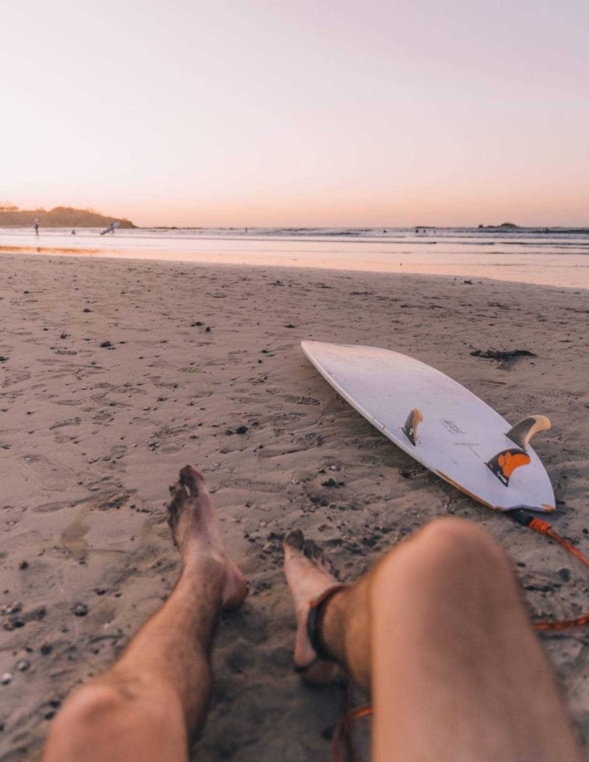 Man sitting on beach in Costa Rica with surfboard