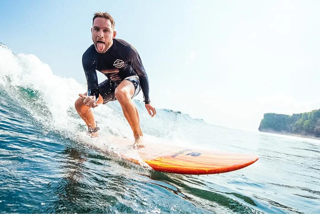 A happy surfer riding wave in Bali beach