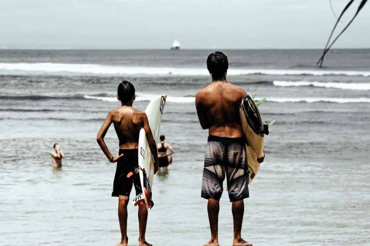 father and son holding up a surfboard