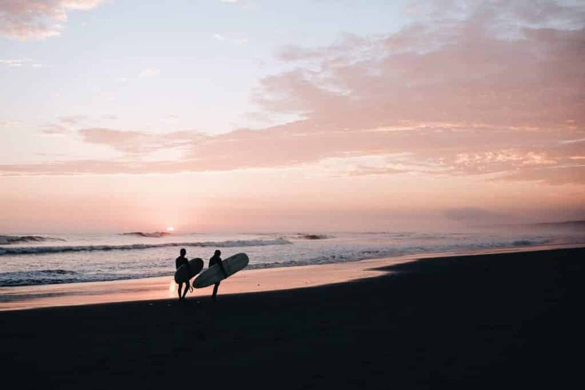 Two people walking along beach after a surf lesson